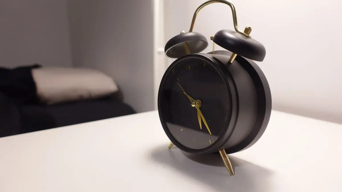 Black alarm clock on a white bedside table