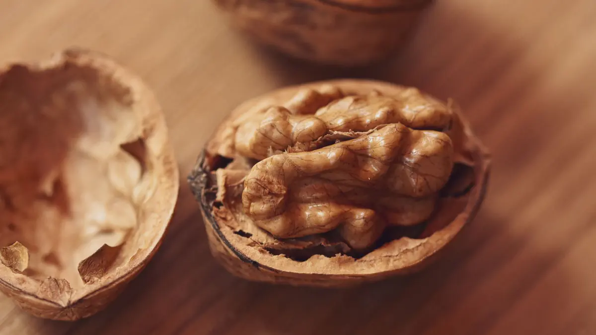 A walnut half-open in its shell on a wooden table, a common size comparison for the prostate