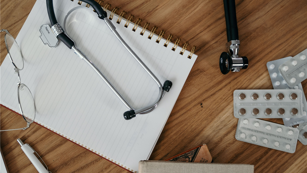 Stethoscope, glasses, and medical notes on a wooden desk, representing the clinical evaluation used to tell prostate conditions apart