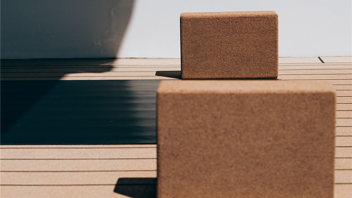 Cork yoga blocks and an exercise mat on a wooden deck, representing a simple home exercise routine