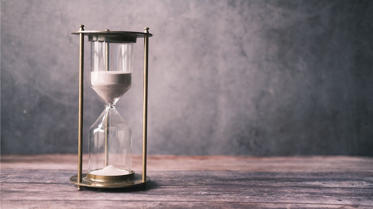 Hourglass with sand on a wooden table, representing how PSA reference ranges change with age