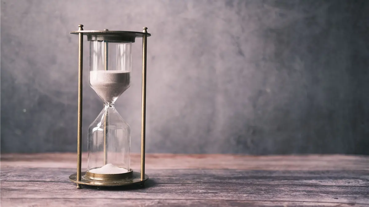 Hourglass with sand on a wooden table, representing how PSA reference ranges change with age