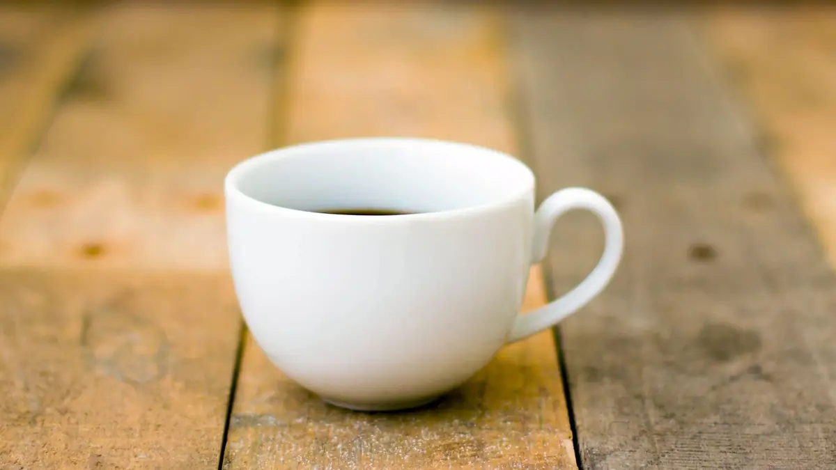 White cup of black coffee on a rustic wooden table