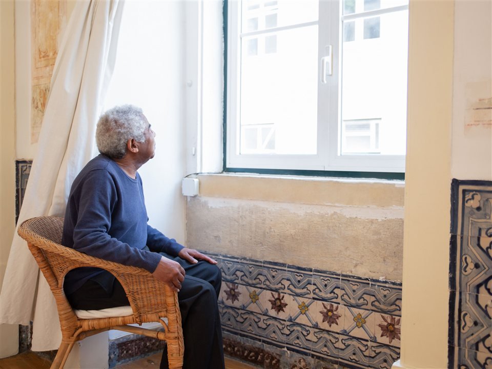 Man in his fifties reading calmly by a bright window with a cup of coffee in the early morning