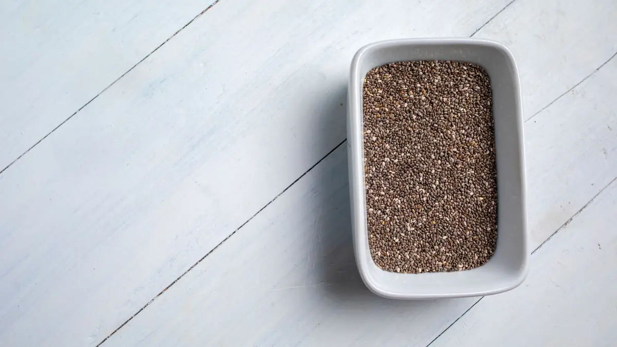 Small seeds in a white ceramic dish on a white wooden table
